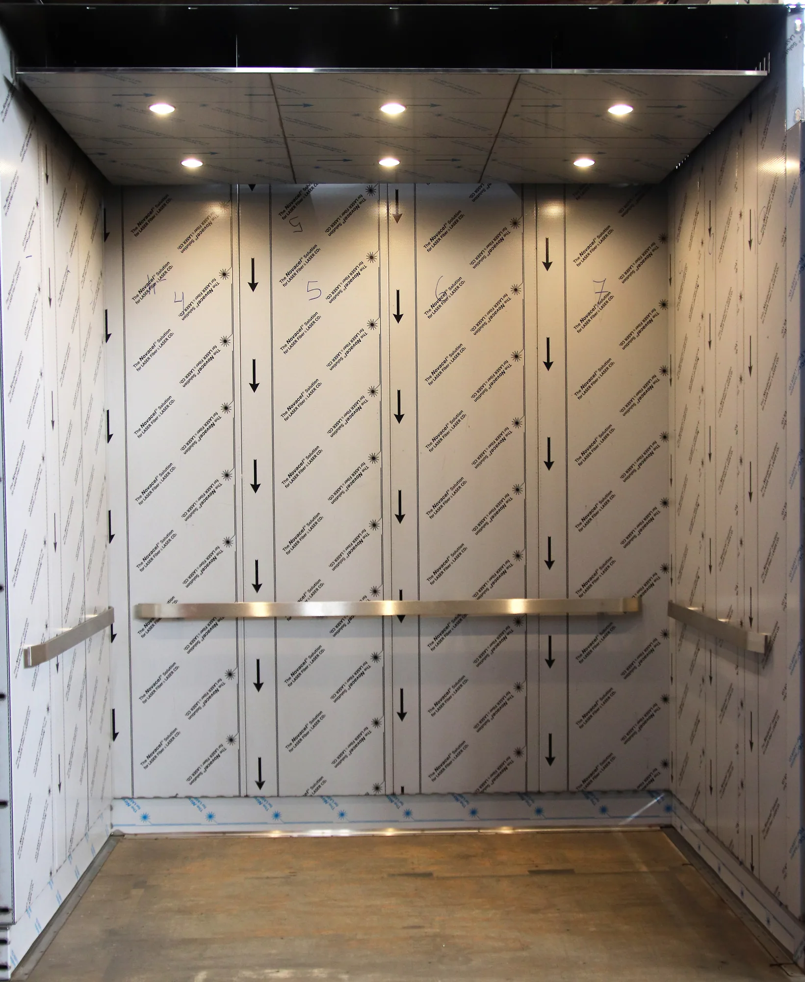 Amtrak elevator cab with patterned stainless wall panels and dark flooring