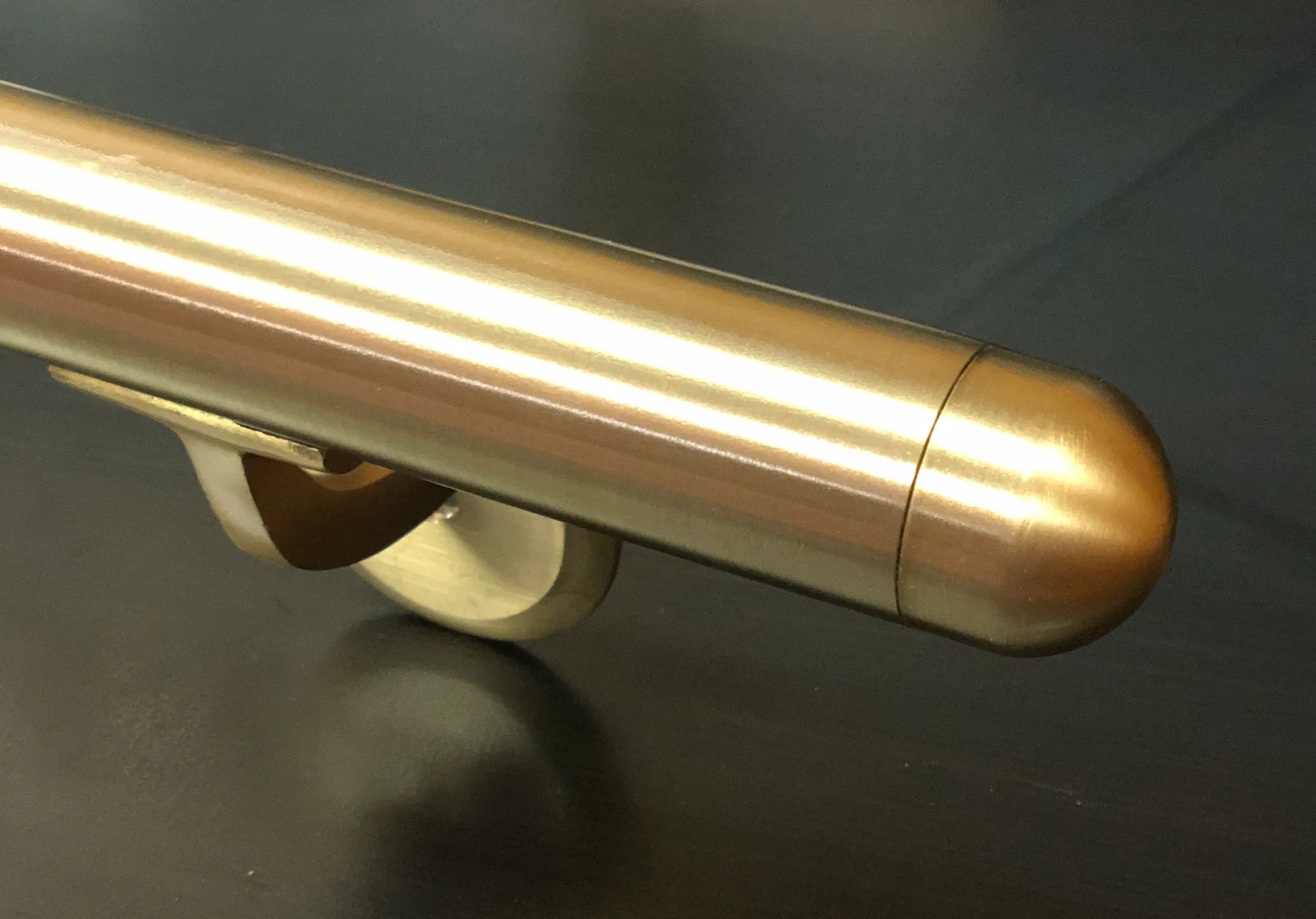 Round bronze elevator handrail with a softly polished end cap