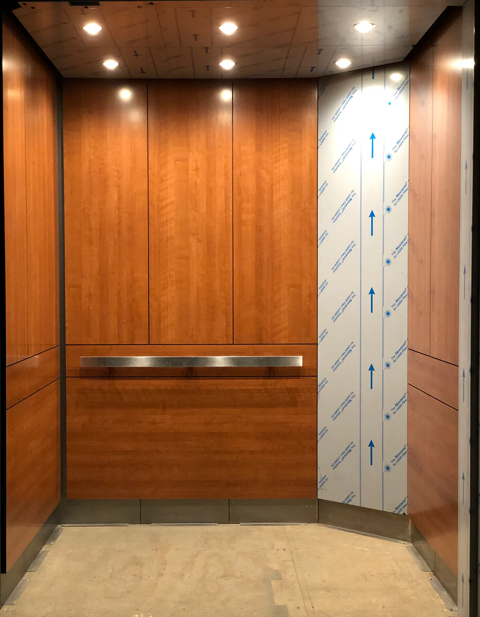 Elevator cab corner post joining warm wall panels and stainless handrails