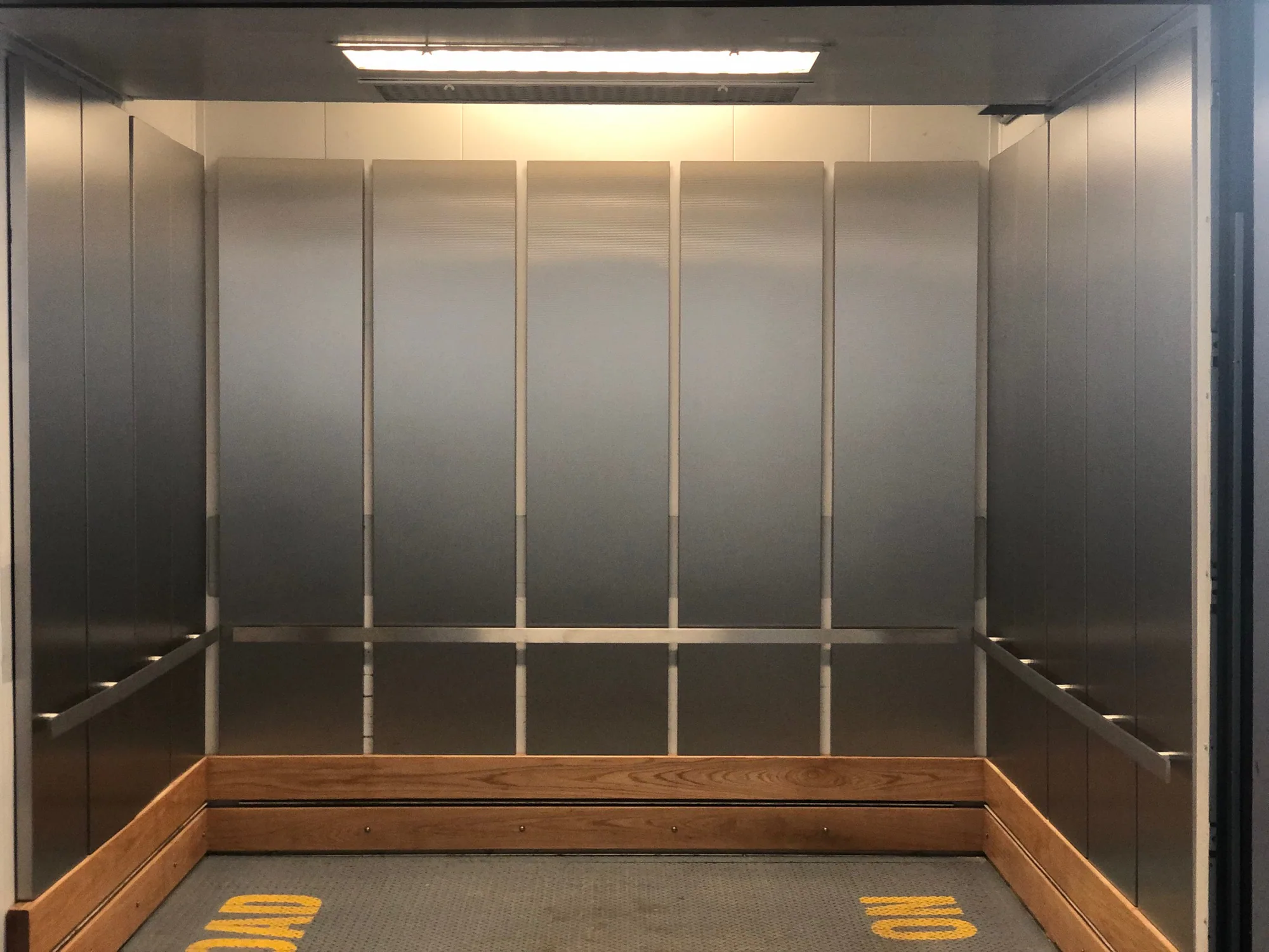 Stainless elevator interior at a Chicago data center with wood lower rail protection
