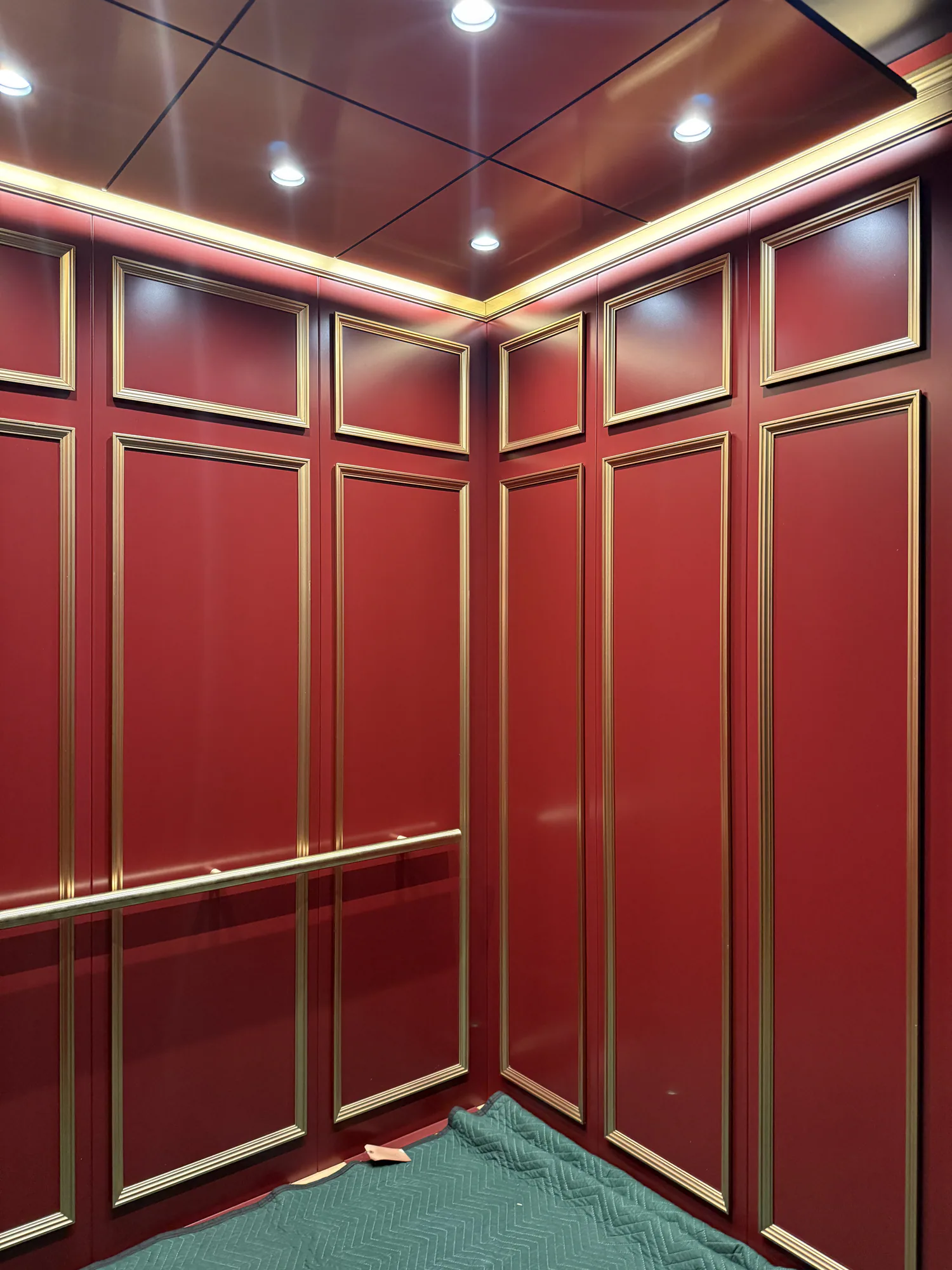 Red architectural elevator panels with metal reveals and matching handrails