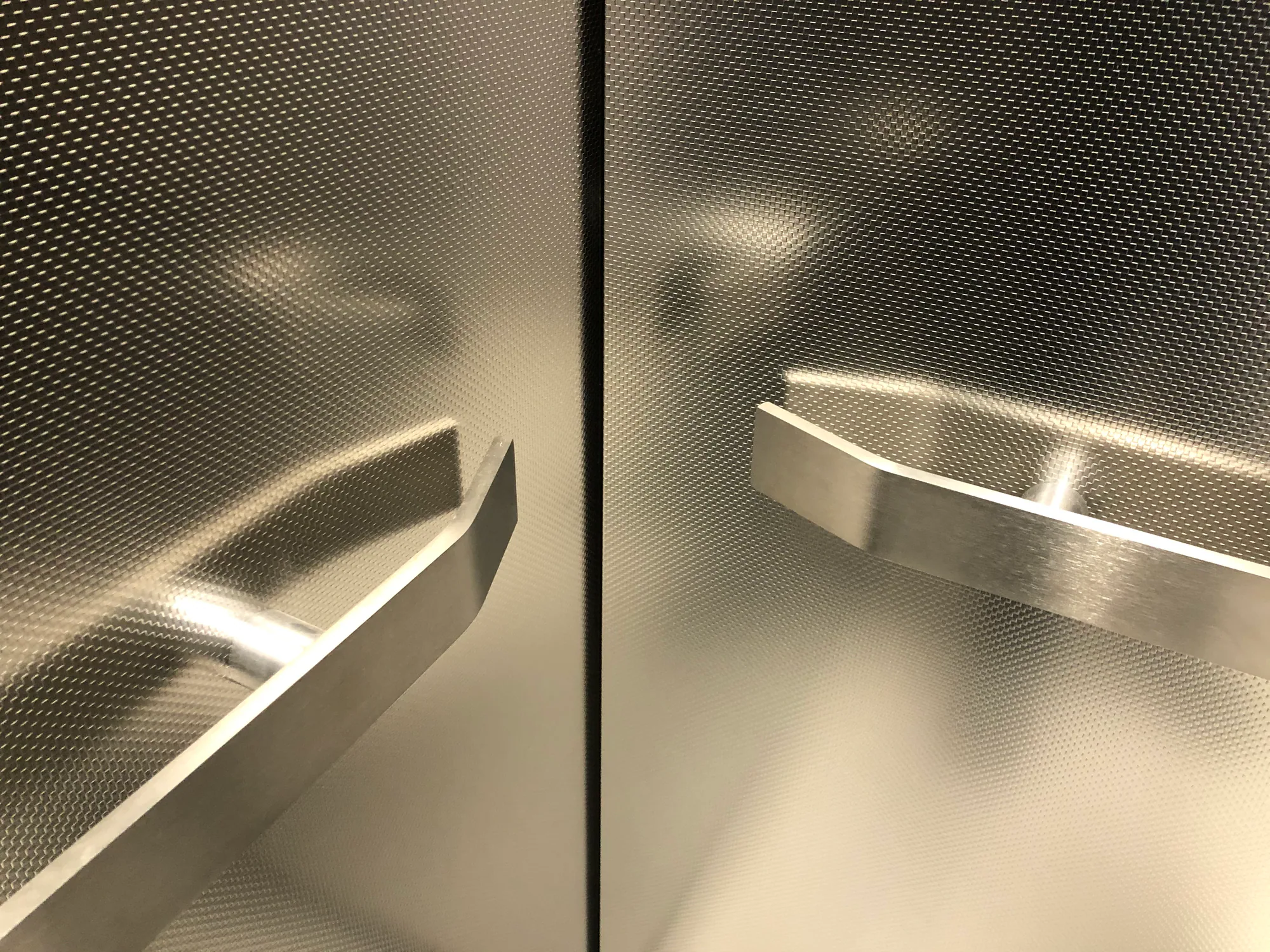 Two stainless elevator handrails installed on dark patterned wall panels