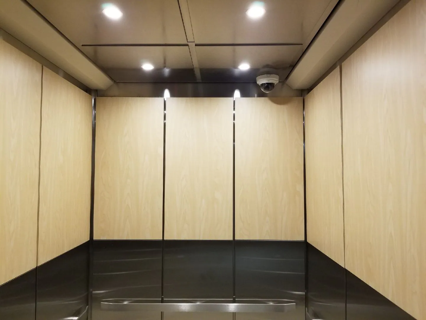 VA hospital elevator cab with light wall panels, dark base panels, and stainless rails
