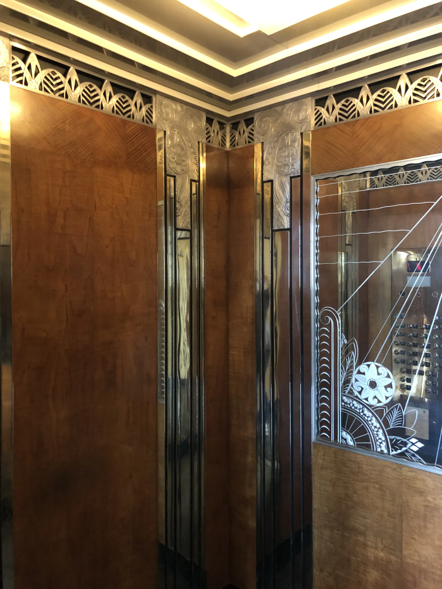 Ornamental bronze elevator interior with mirrored panels and decorative trim