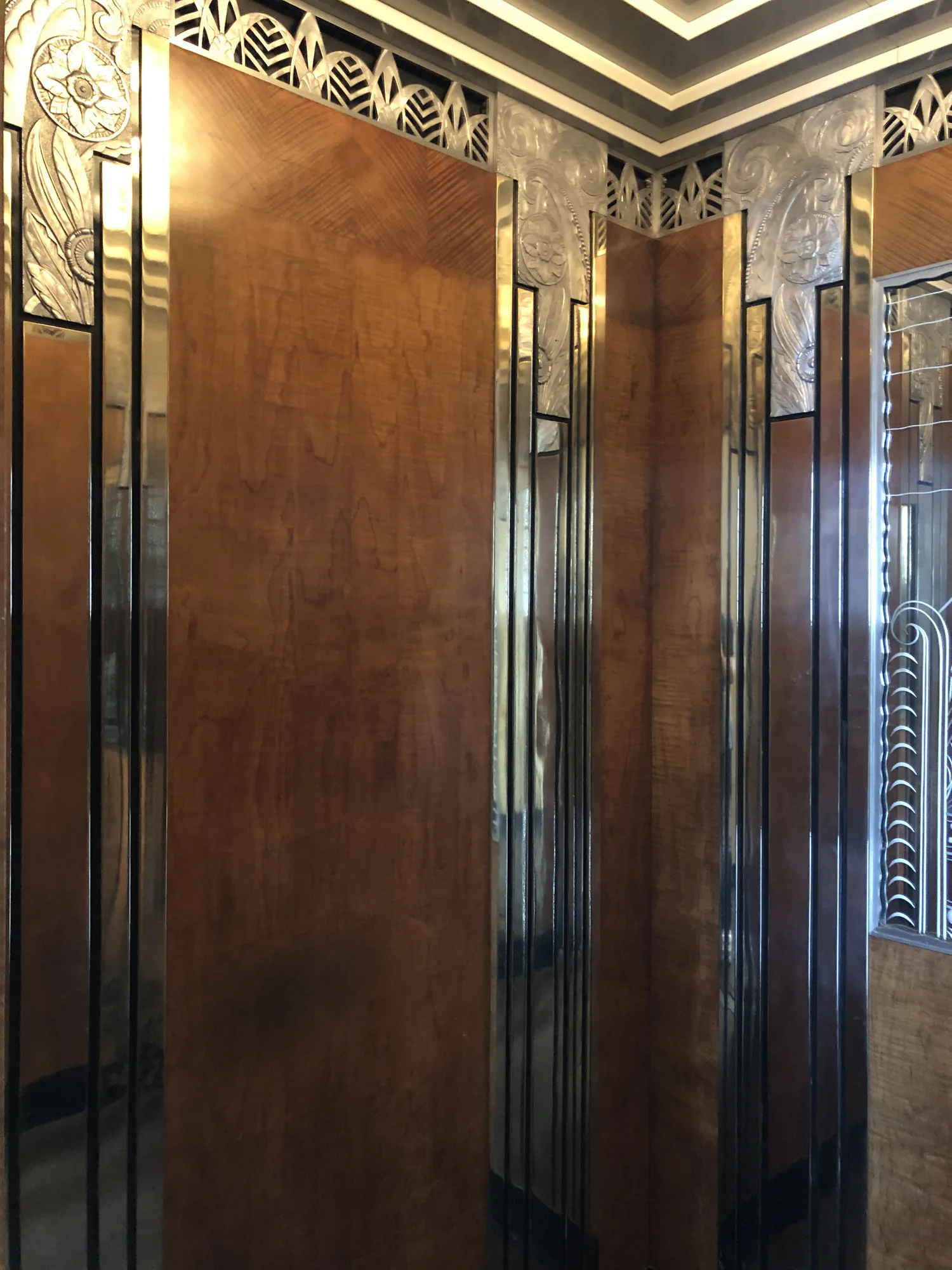 Close view of decorative bronze elevator panels and polished mirrored surfaces