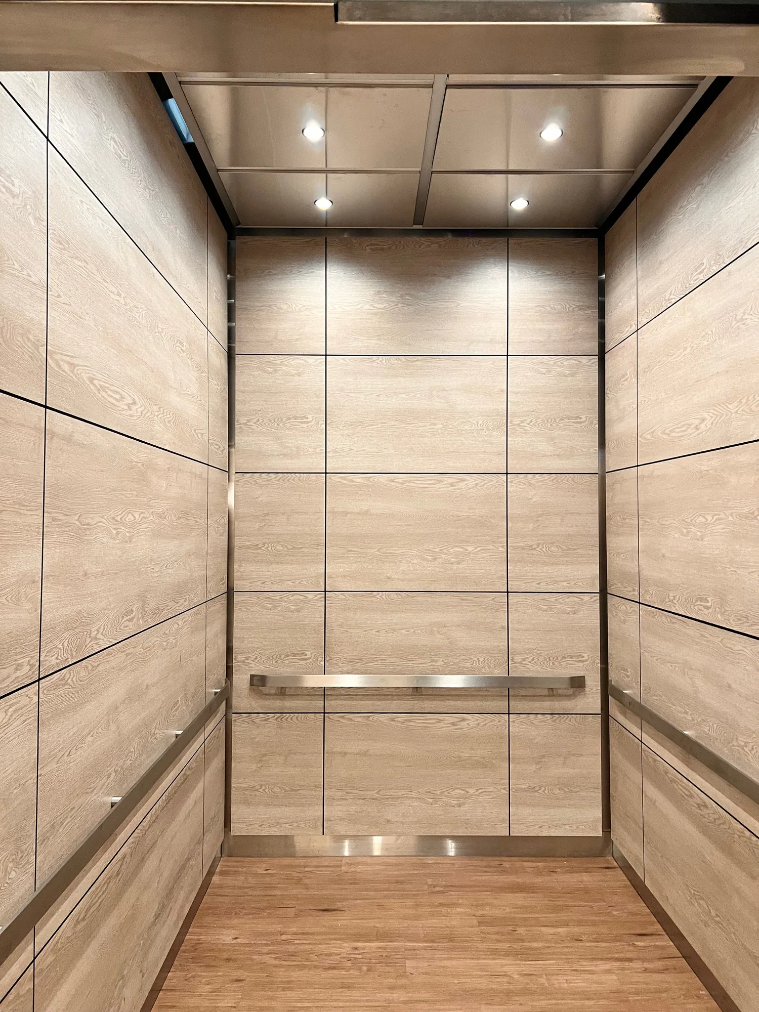 Chicago senior living elevator interior with light stone-look panels and stainless handrails