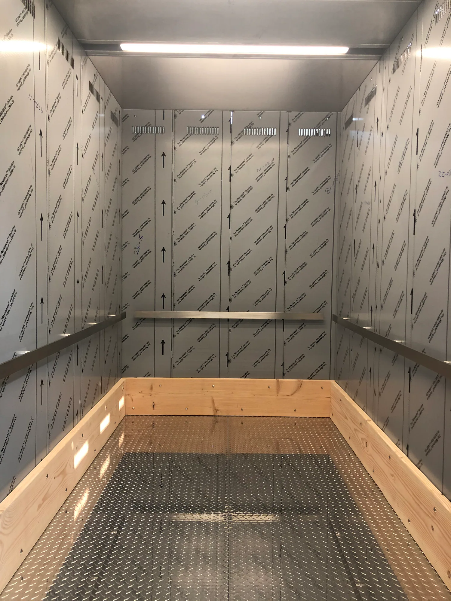 Freight elevator interior with protective wall covering and heavy wood bumper rails